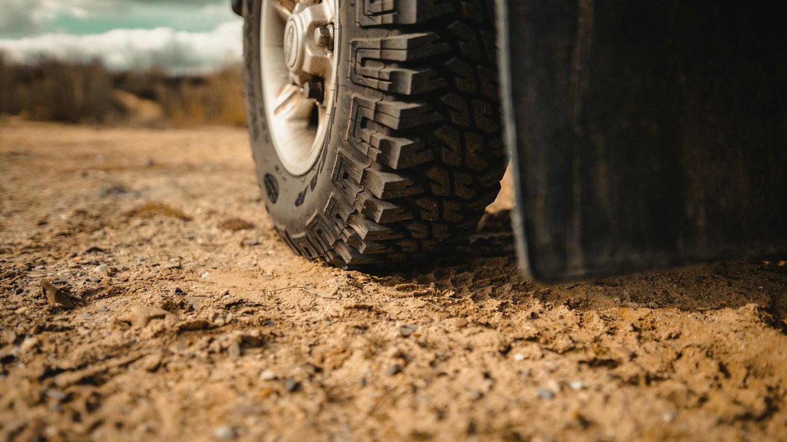 Aired-down off-road tire flexing against sandy trail terrain