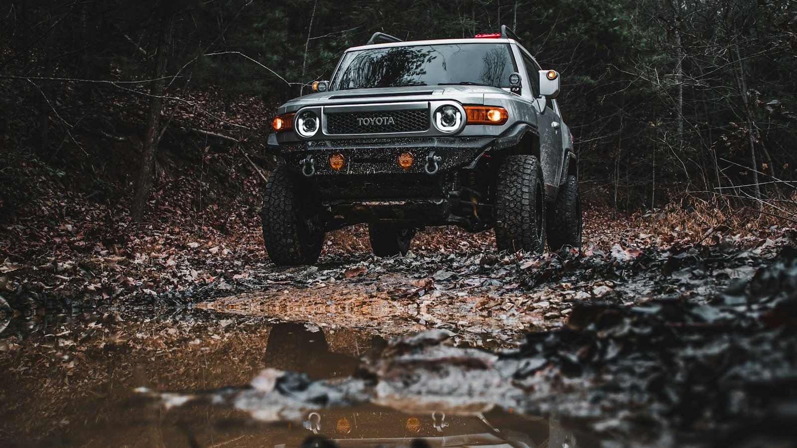A Jeep fording a muddy trail through a winter forest