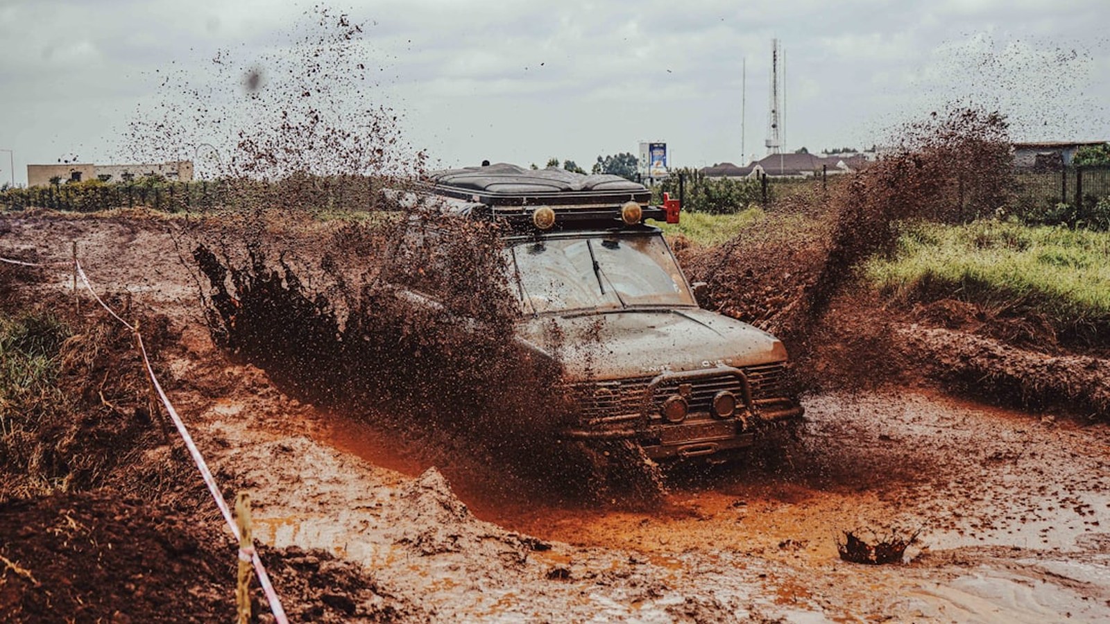 A 4x4 truck plowing through deep mud with a big spray, using steady momentum to keep moving