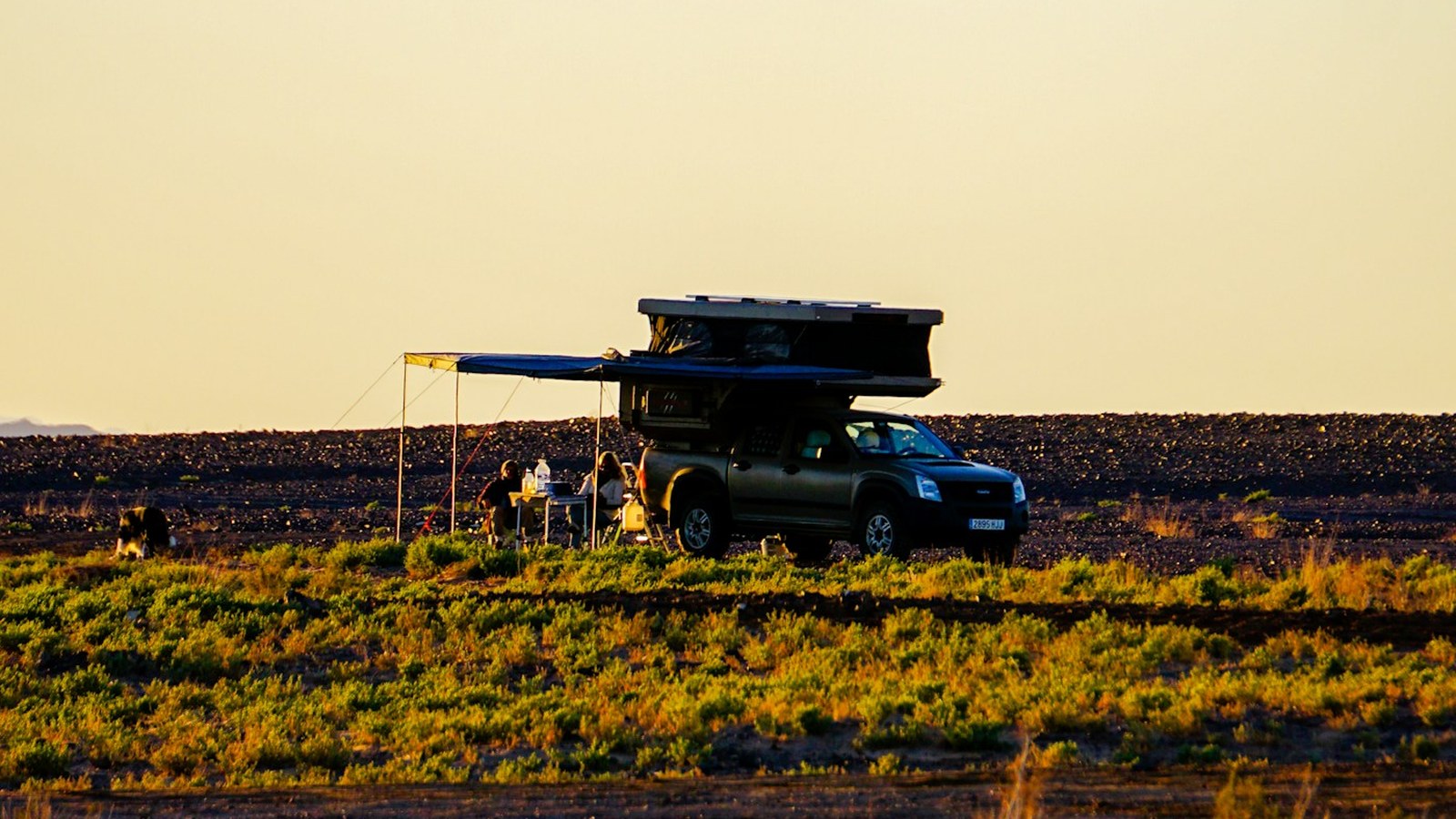 Overland rig with a rooftop tent and awning set up at a remote camp at golden hour