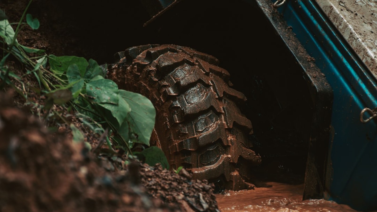 Close-up of an aggressive mud-terrain tire tread caked in dirt on the trail