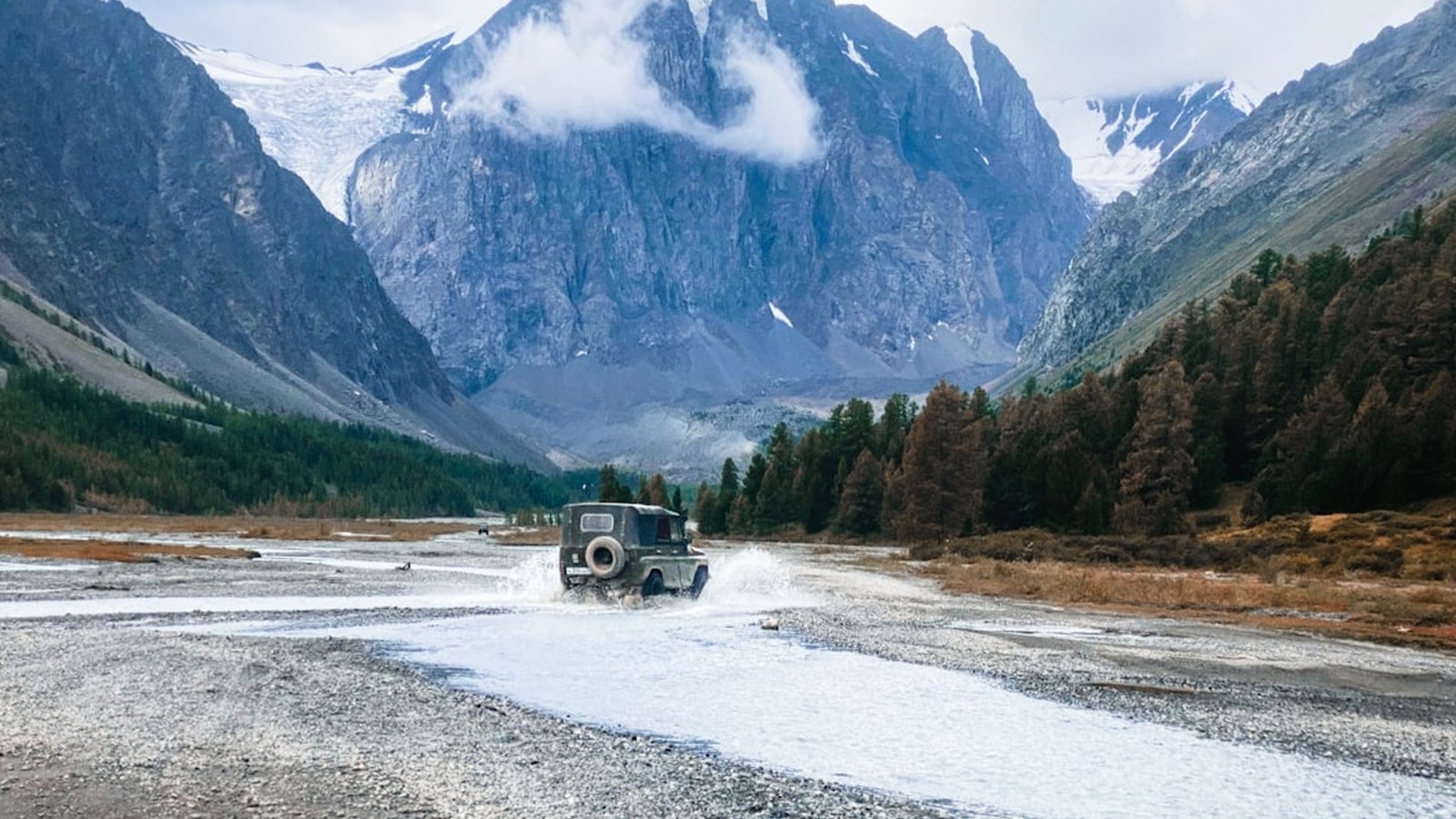 A 4x4 crossing a river pushing a clean bow wave in front of the bumper