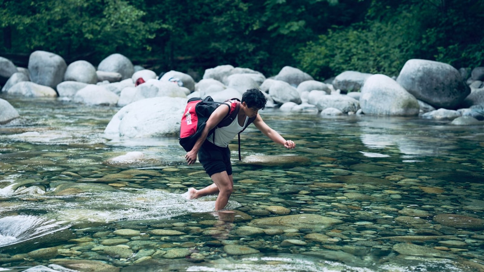 A person wading across a shallow river crossing to check depth before driving