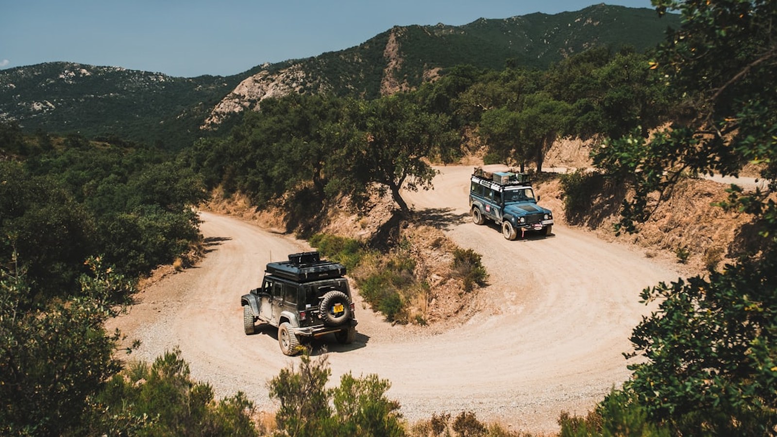 Two 4x4s working a winding switchback trail together