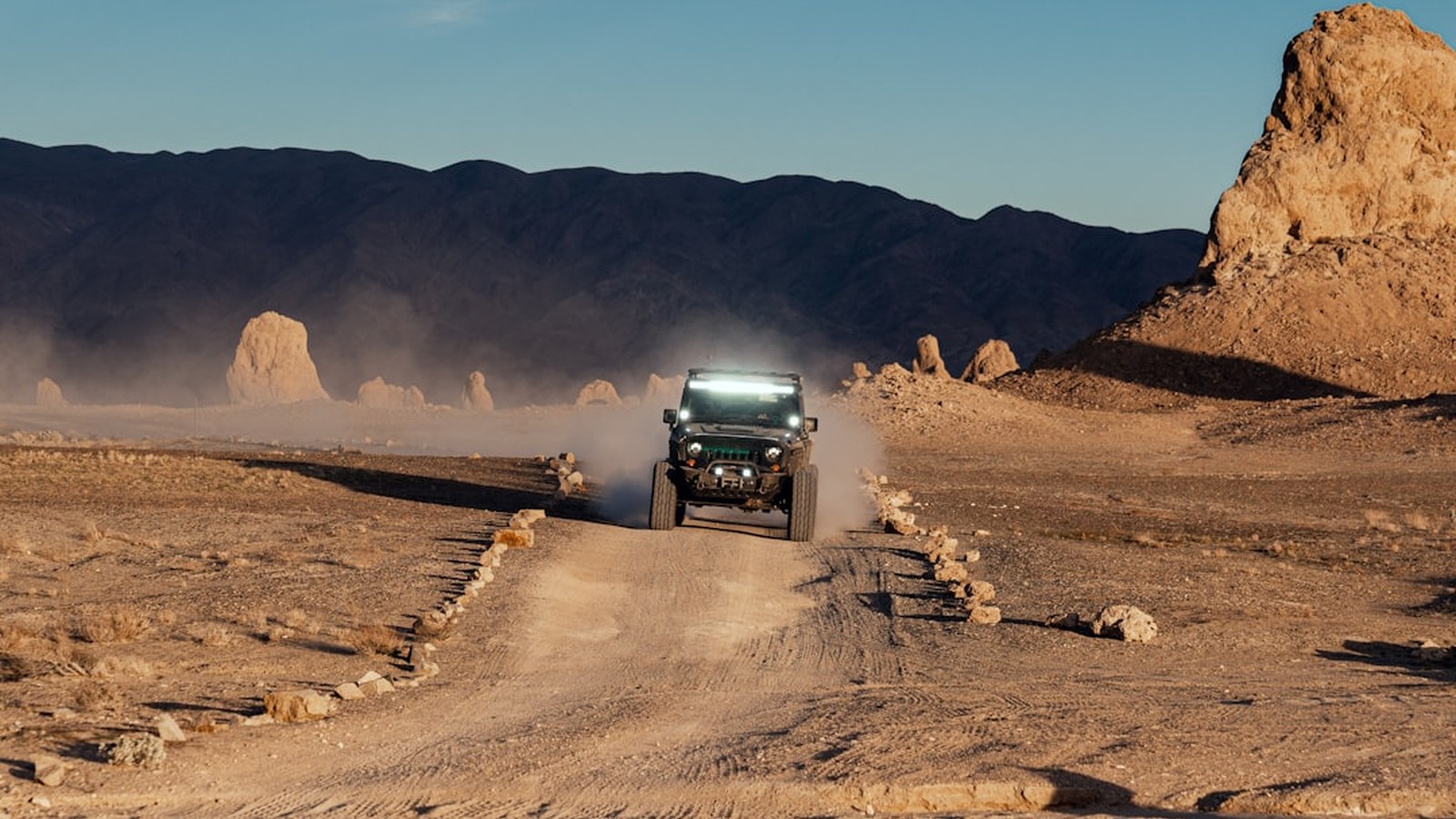 An SUV kicking up dust on a rocky desert trail