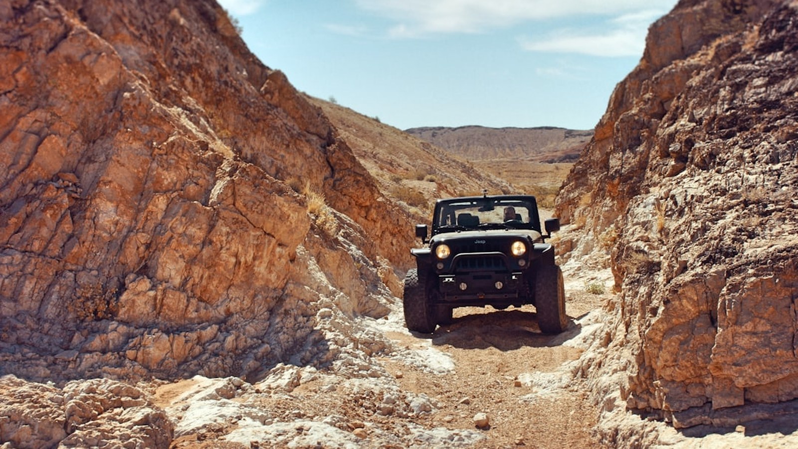 A built 4x4 crawling through a rocky canyon wash, extreme numeric-rated terrain