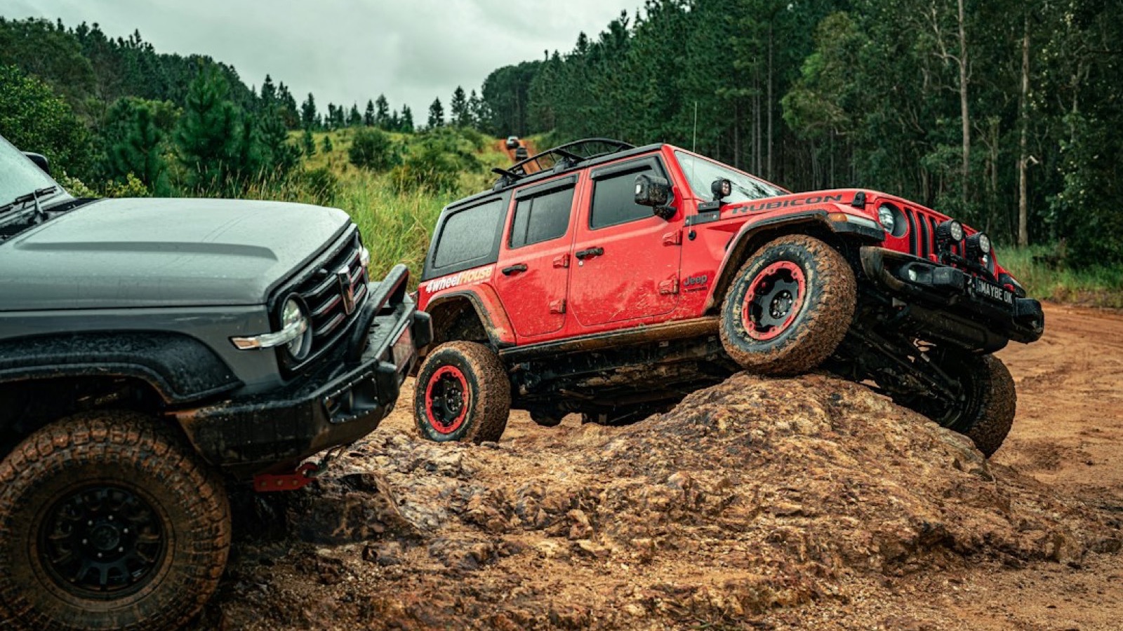 Lifted Jeep Wrangler Rubicon crawling over a red rock ledge with a second 4x4 behind it