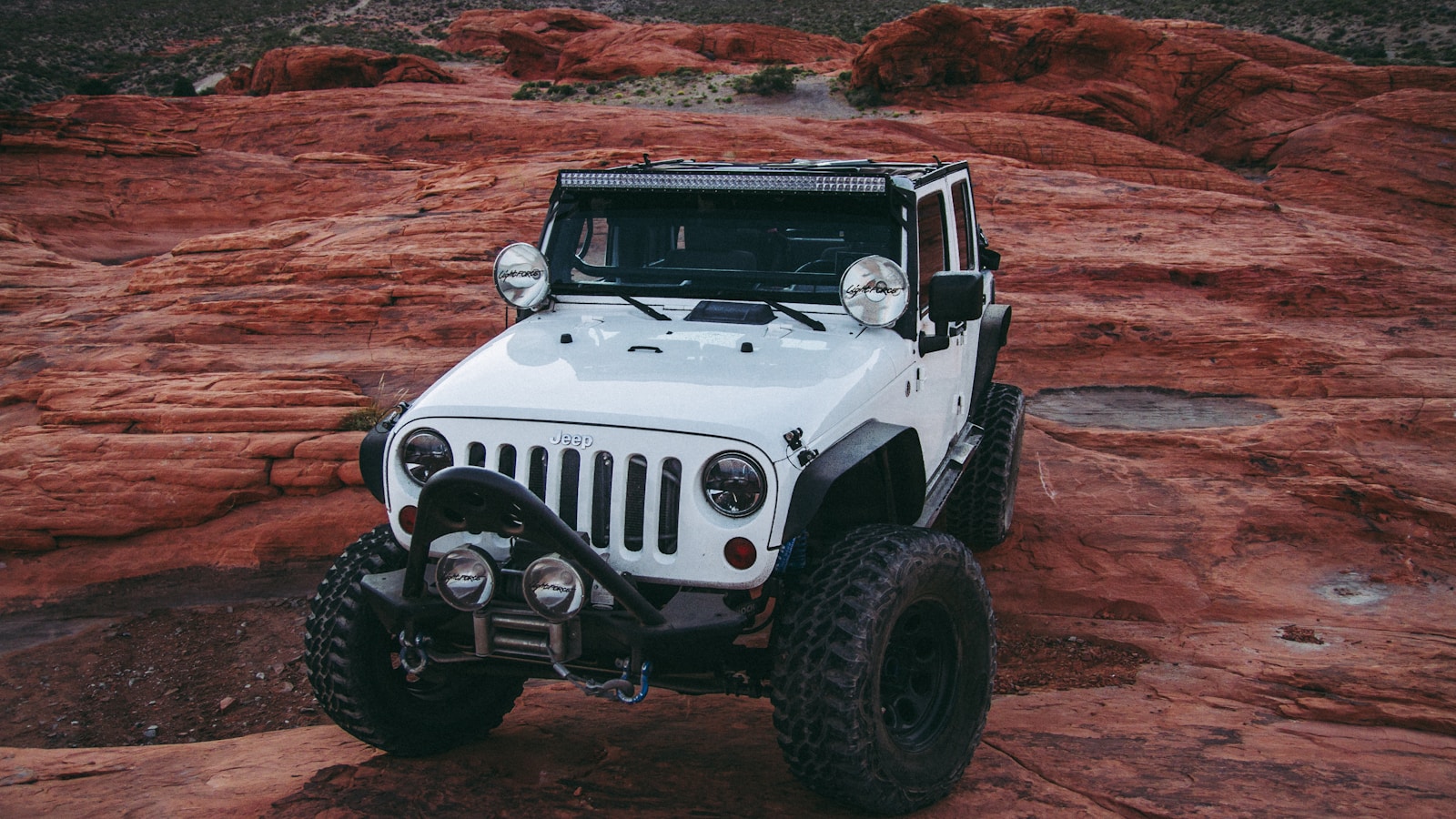 A built Jeep Wrangler on a steep red-rock ledge