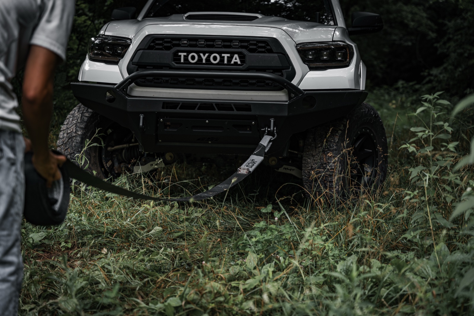 A tow strap with sewn loop ends rigged to a rated shackle on a Toyota Tacoma's front bumper