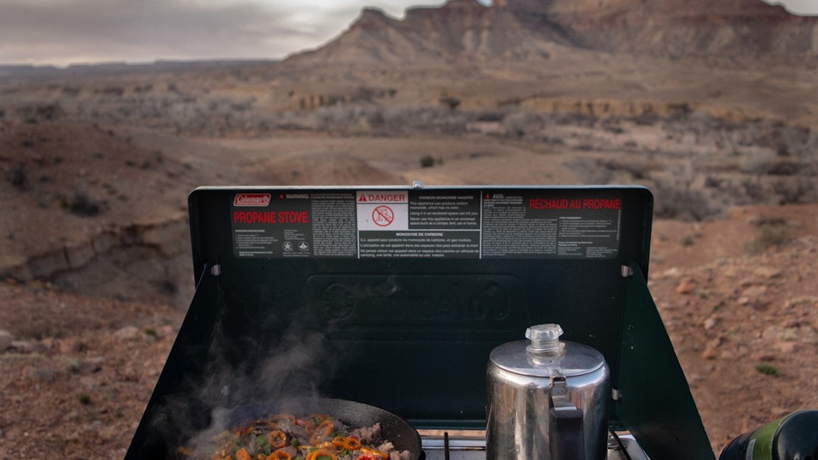 A camp kitchen setup with a portable stove and cooking gear at an overland campsite