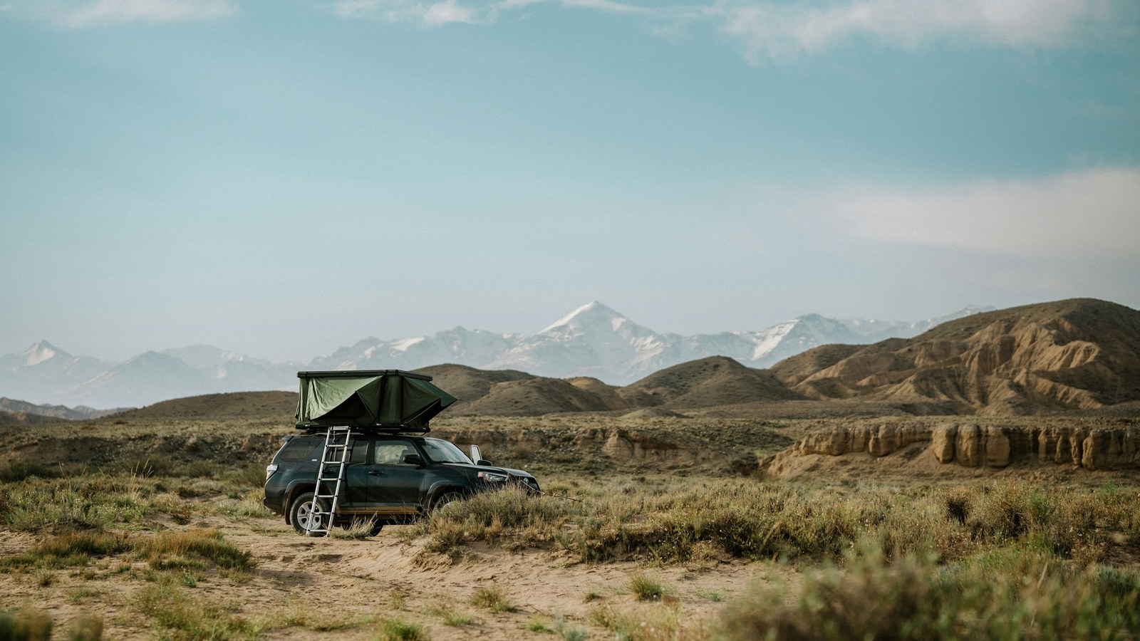 4x4 rig with a rooftop tent parked at a remote camp in dry mountainous terrain