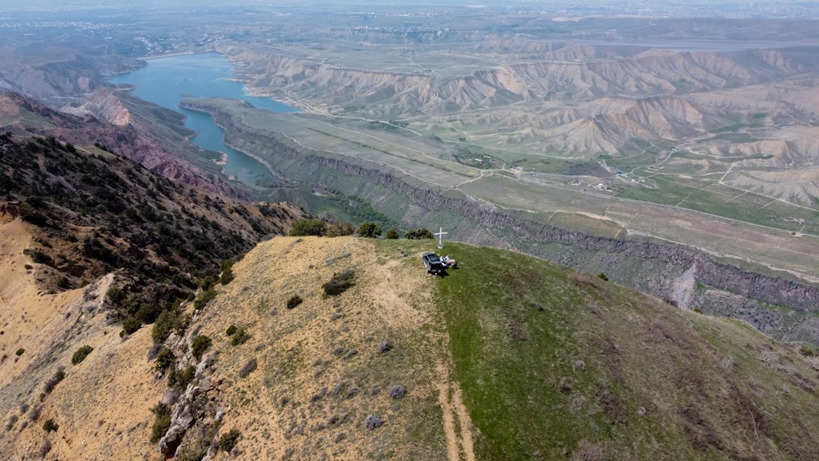 A lone 4x4 rig perched on a high ridge overlooking a sprawling valley