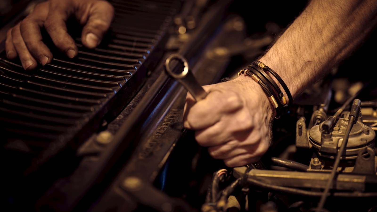 Mechanic using a wrench on an engine, representing a quick hands-on post-trail check and grease job