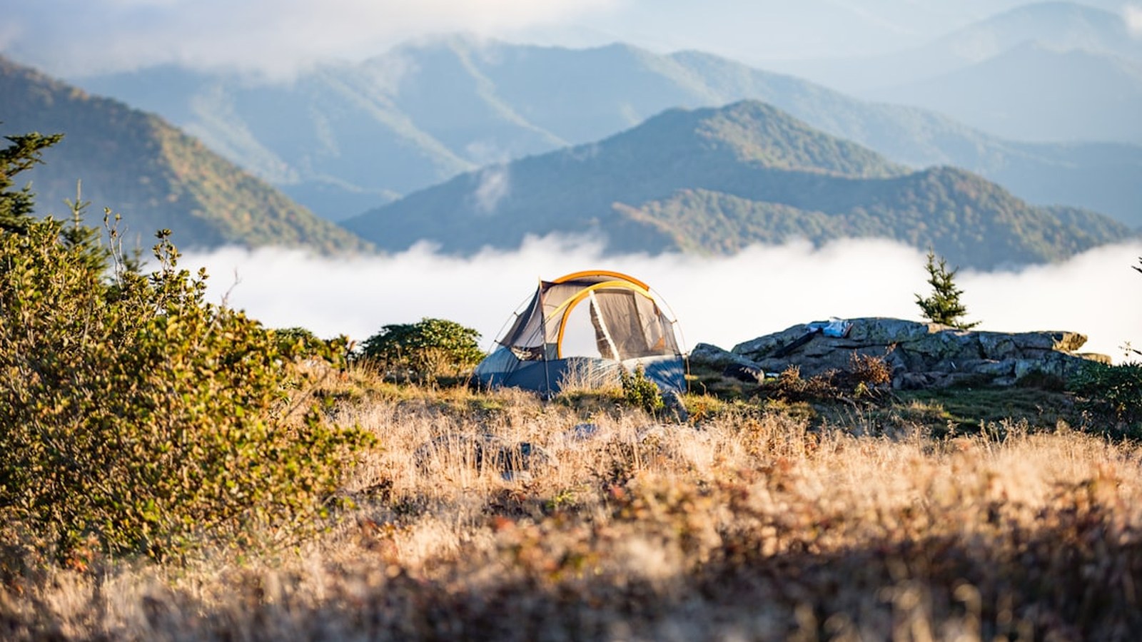 Ground tent pitched on a high ridgeline above the clouds at golden hour