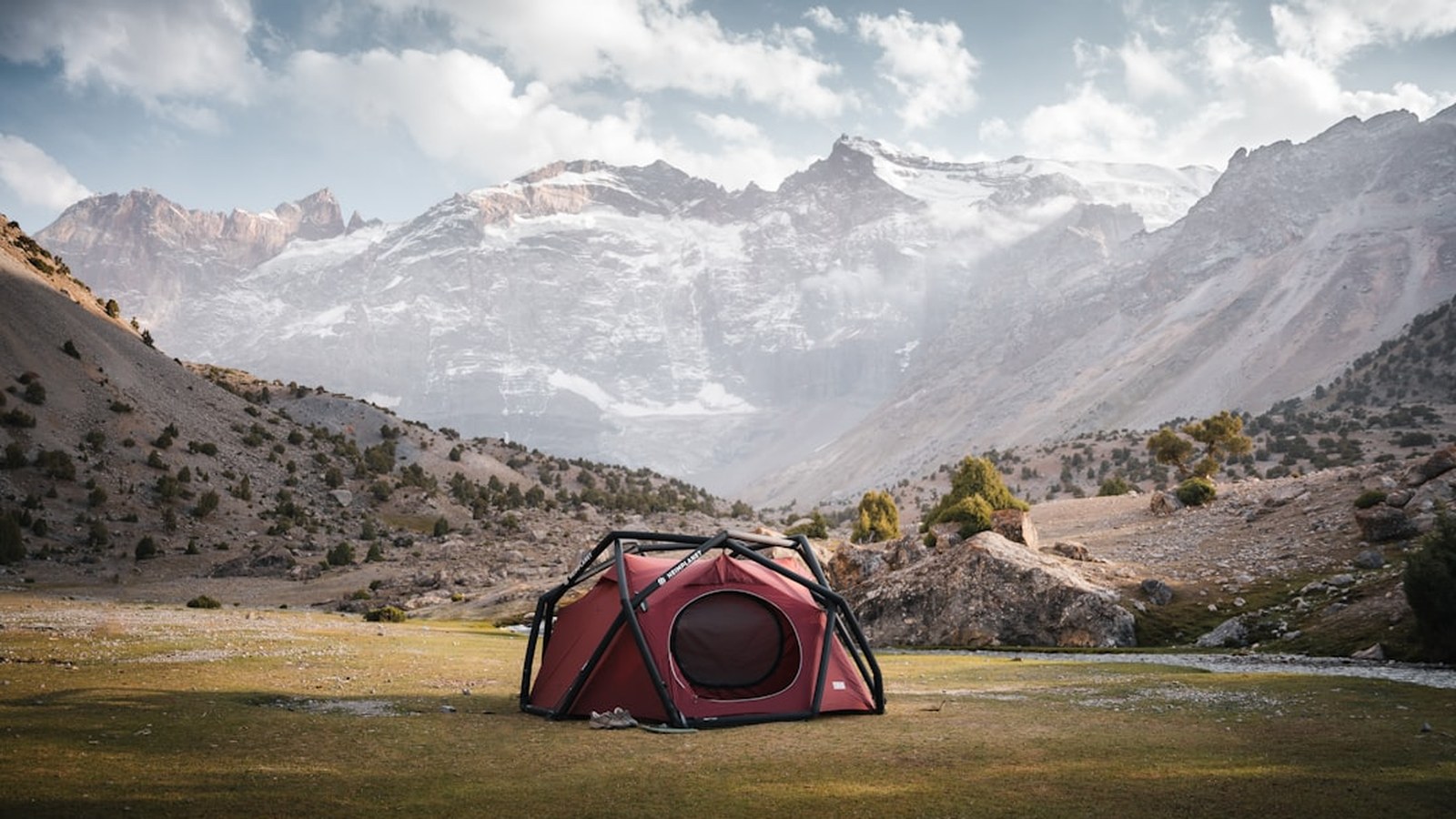 Spacious dome tent pitched alone in a dramatic alpine valley