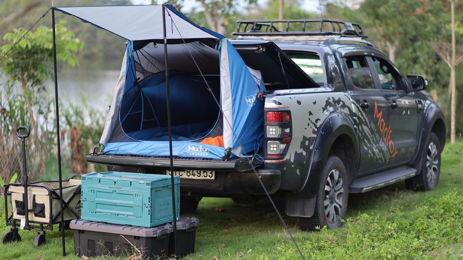 Overland pickup truck loaded with gear and a rooftop tent parked at a backcountry camp