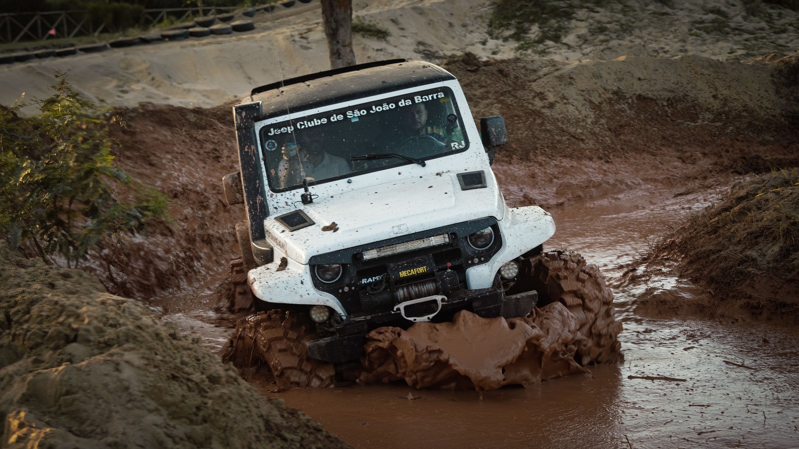A 4x4 plowing through a deep mud pit with spray flying off the front wheels