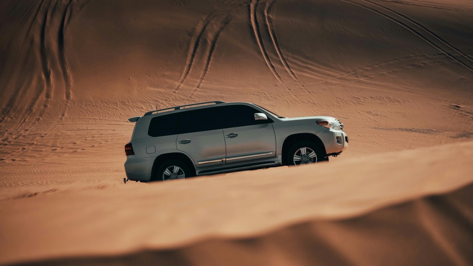 A 4x4 crossing soft desert dunes, the kind of sand where recovery boards earn their keep