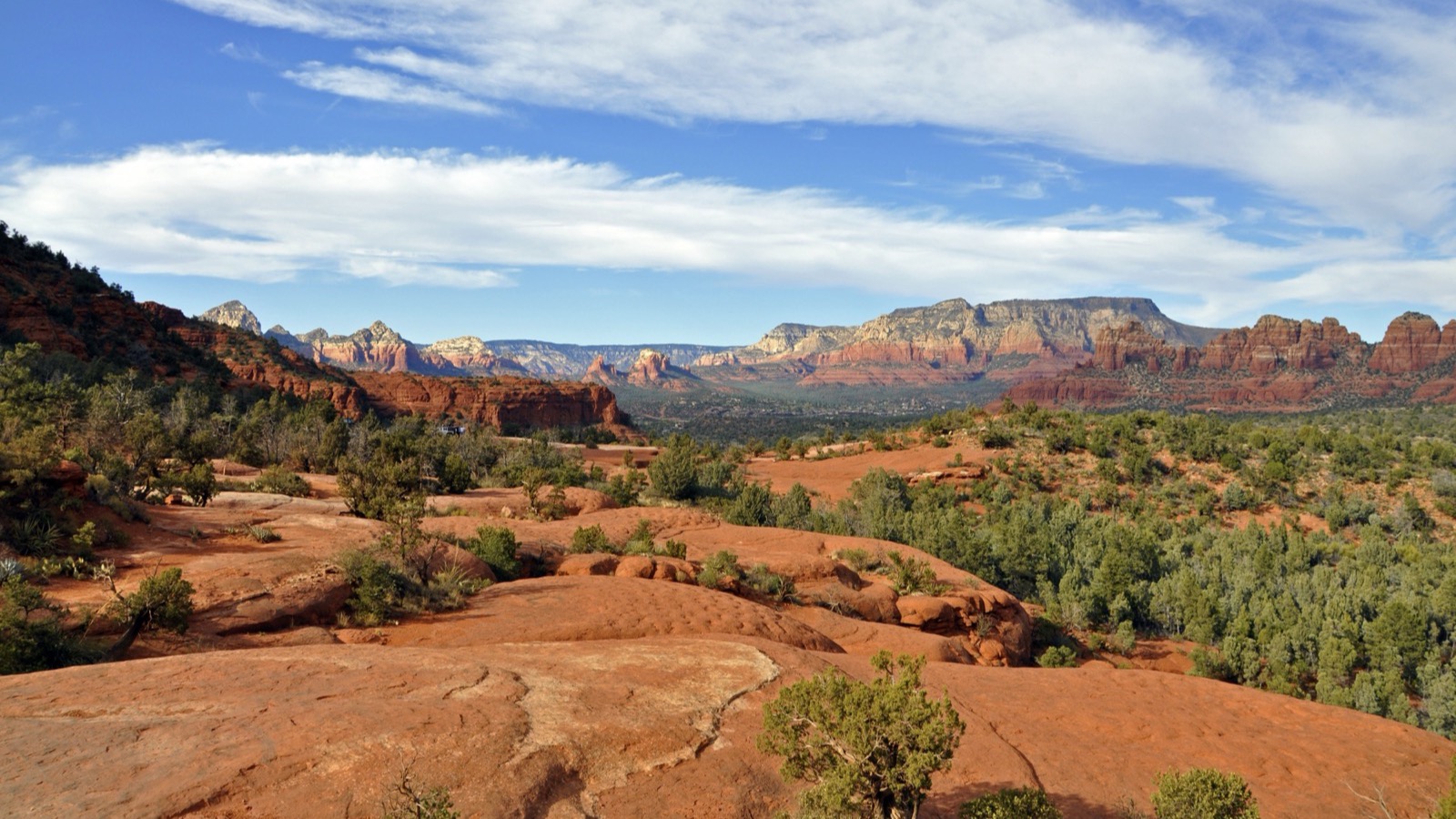 Sweeping red slickrock and layered Sedona buttes seen from the Broken Arrow Trail under a blue sky