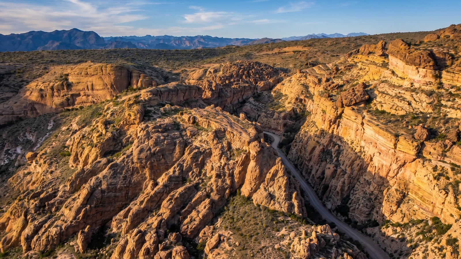 A narrow one-lane dirt shelf road cut into the golden cliffs of Fish Creek Canyon on the Apache Trail
