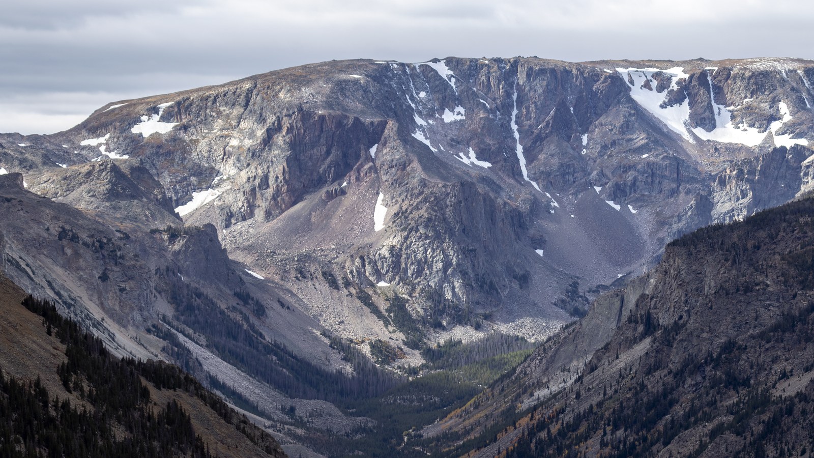 A glacier-carved cirque and U-shaped valley in the Beartooth Mountains, with snow patches clinging to the talus slopes below rugged peaks