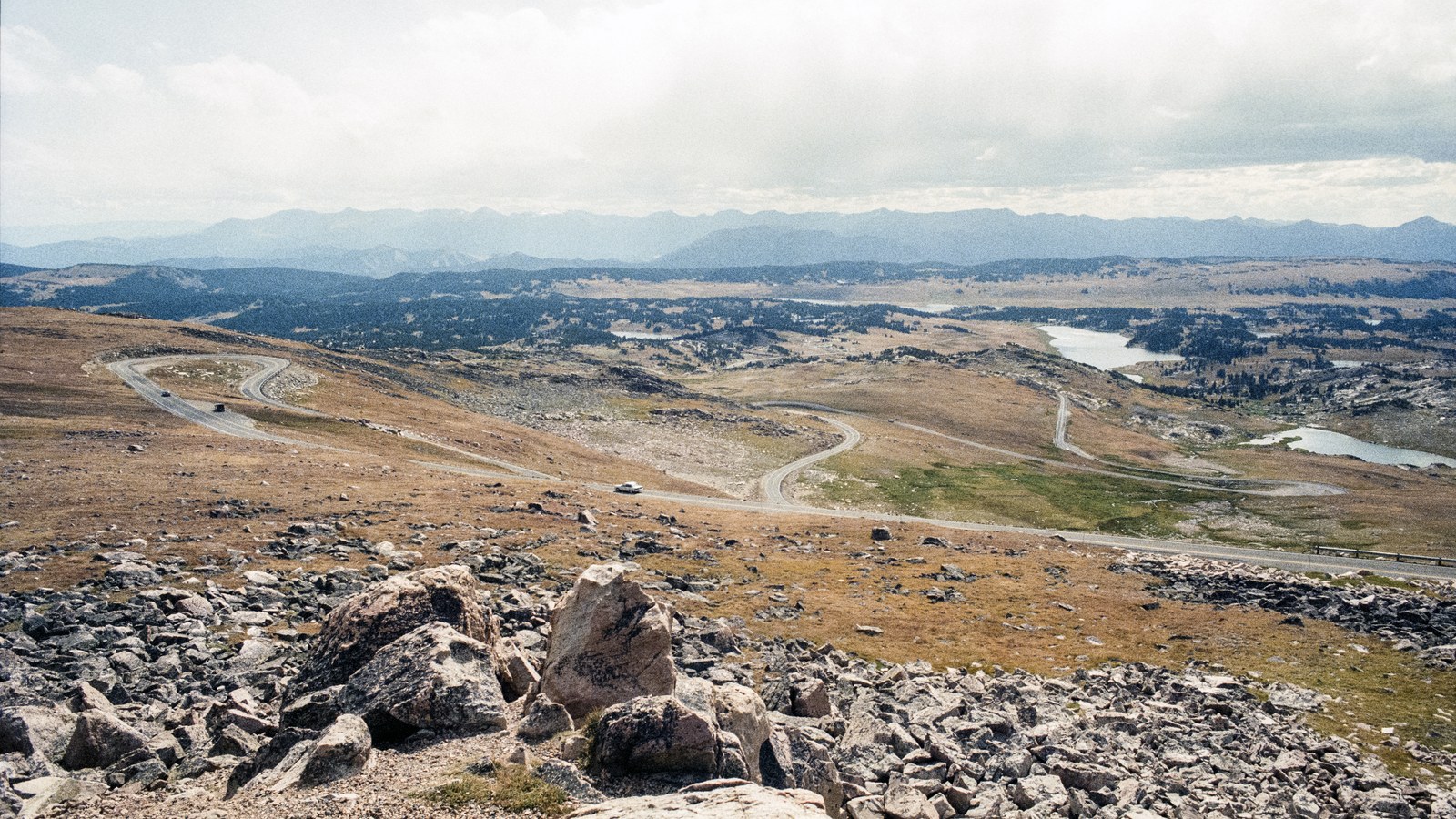 Sweeping switchback curves of the Beartooth Highway descending across the high alpine plateau toward distant ranges and lakes