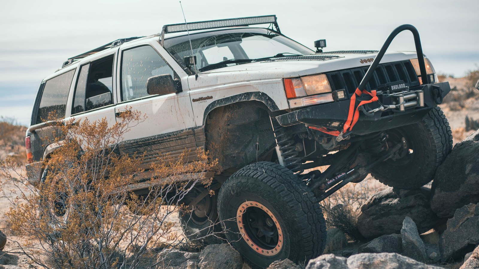 A four-wheel-drive rig picking a line up a rocky desert ledge, the kind of careful tire placement Box Canyon's obstacles demand.