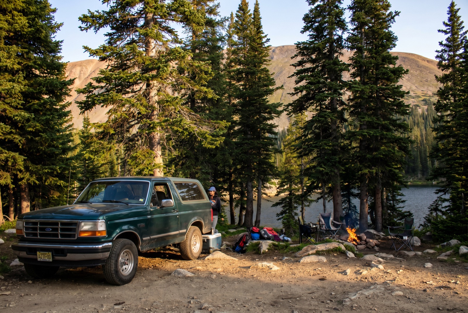 A calm alpine lake ringed by granite boulders and sparse timberline conifers, the kind of lakeside camping Chinns Lake delivers