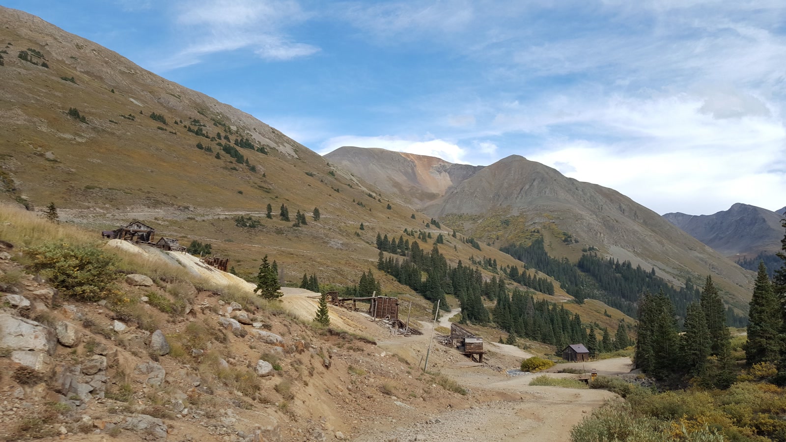 Weathered cabins along the road near Animas Forks with a colorful San Juan peak rising behind