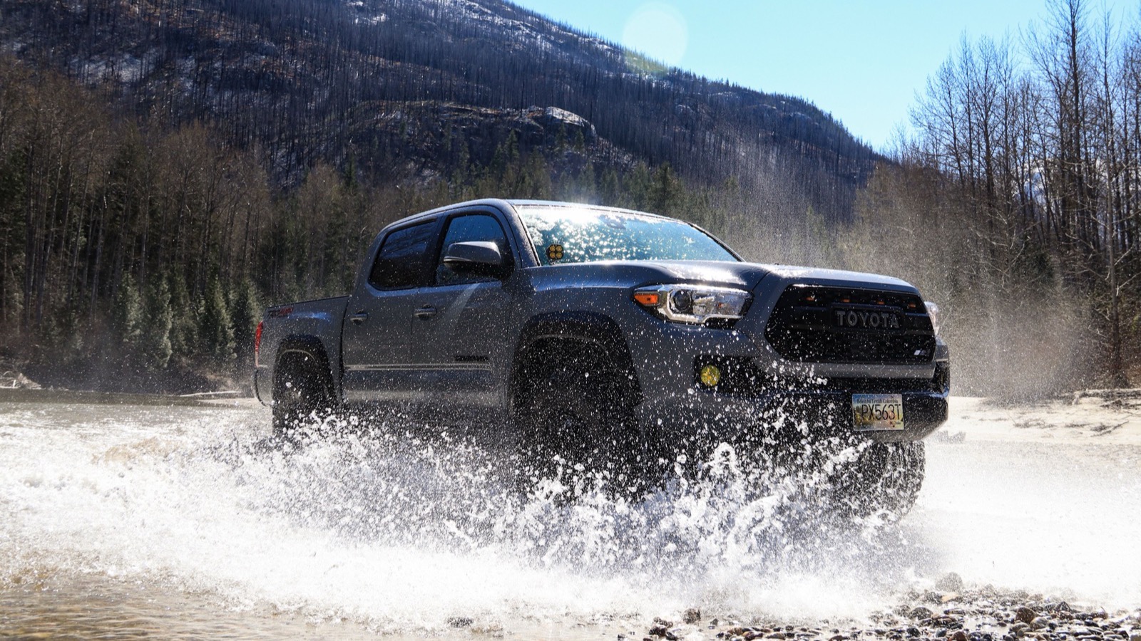 A 4x4 truck blasting through a mountain river crossing with a wall of spray, the kind of water that defines a Fordyce run