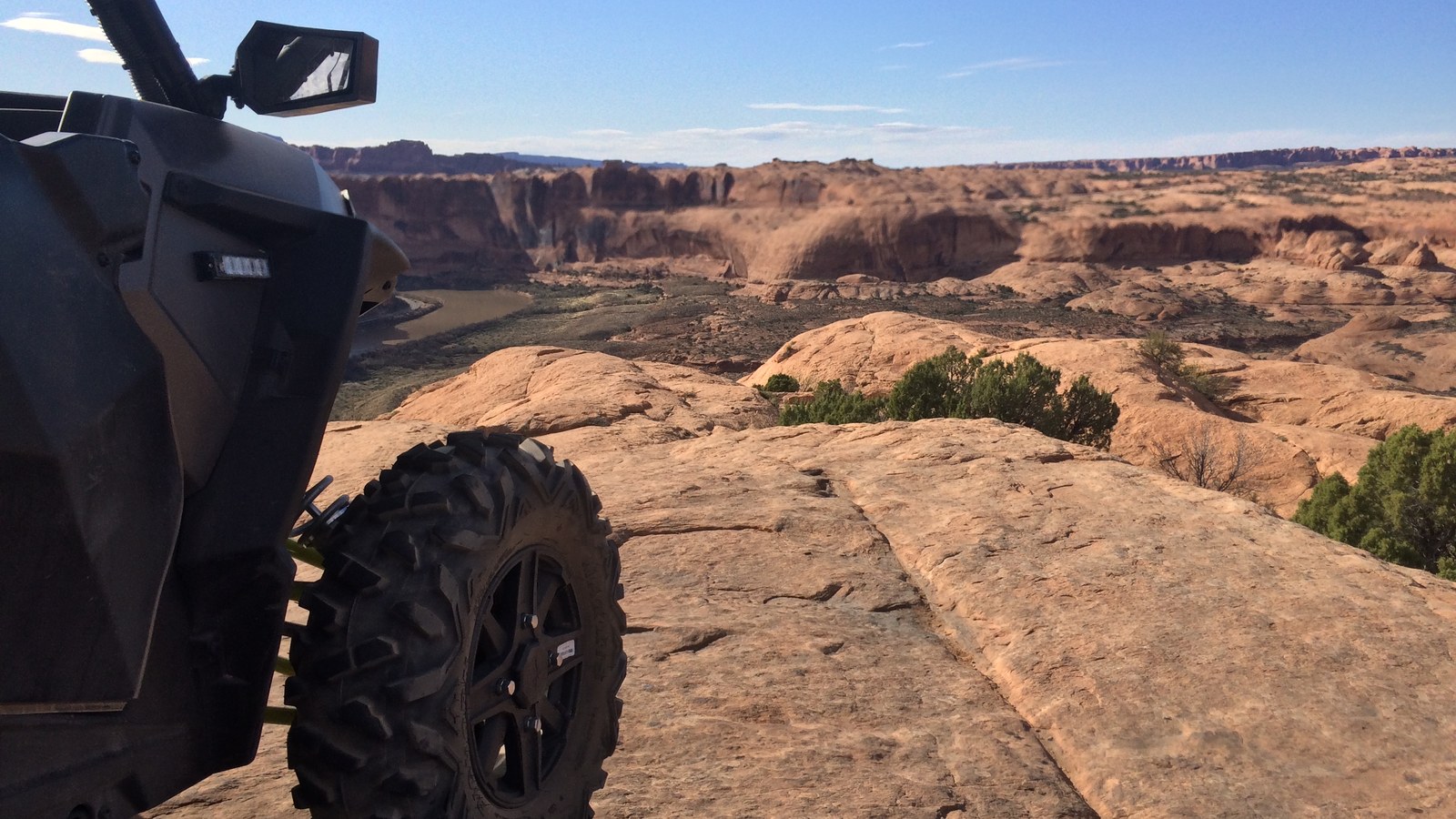 A side-by-side on the slickrock of Hell's Revenge at an overlook above the canyon country near Moab