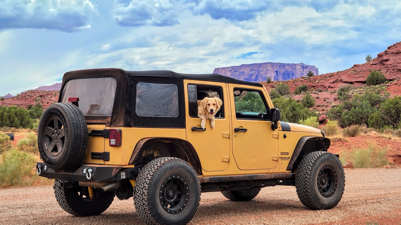 A Jeep Wrangler on red Moab terrain beneath dramatic desert skies near the Sand Flats Recreation Area