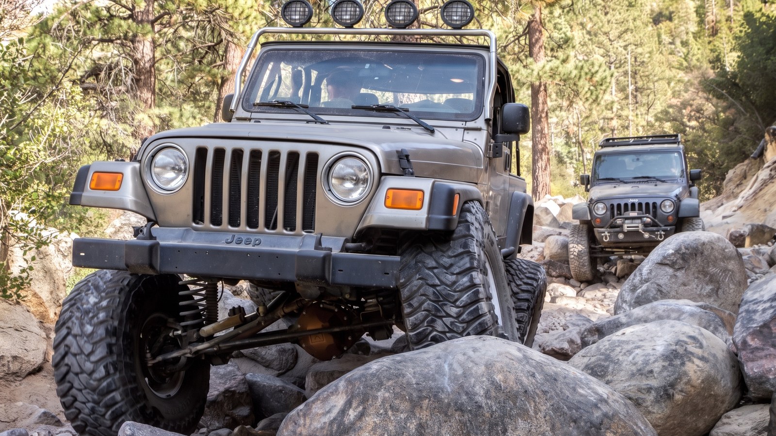 Two modified 4x4s crawling the gatekeeper boulder section at the west end of Holcomb Creek.