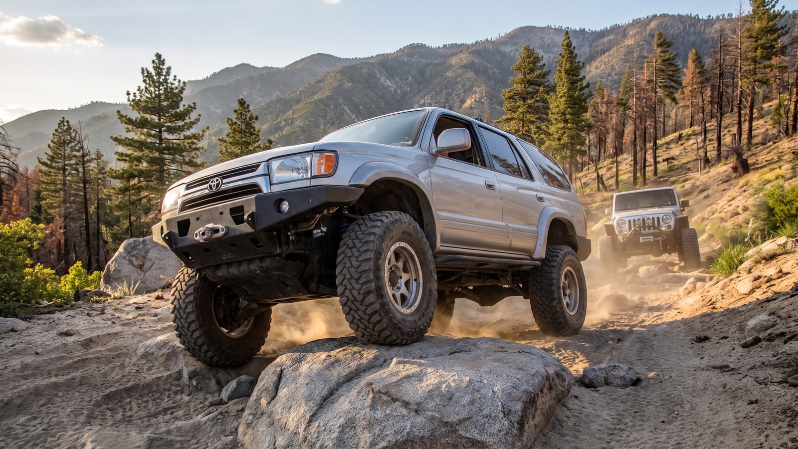 A modified 4x4 climbing a granite boulder step on Holcomb Creek with a second rig ahead and the San Bernardino forest behind.