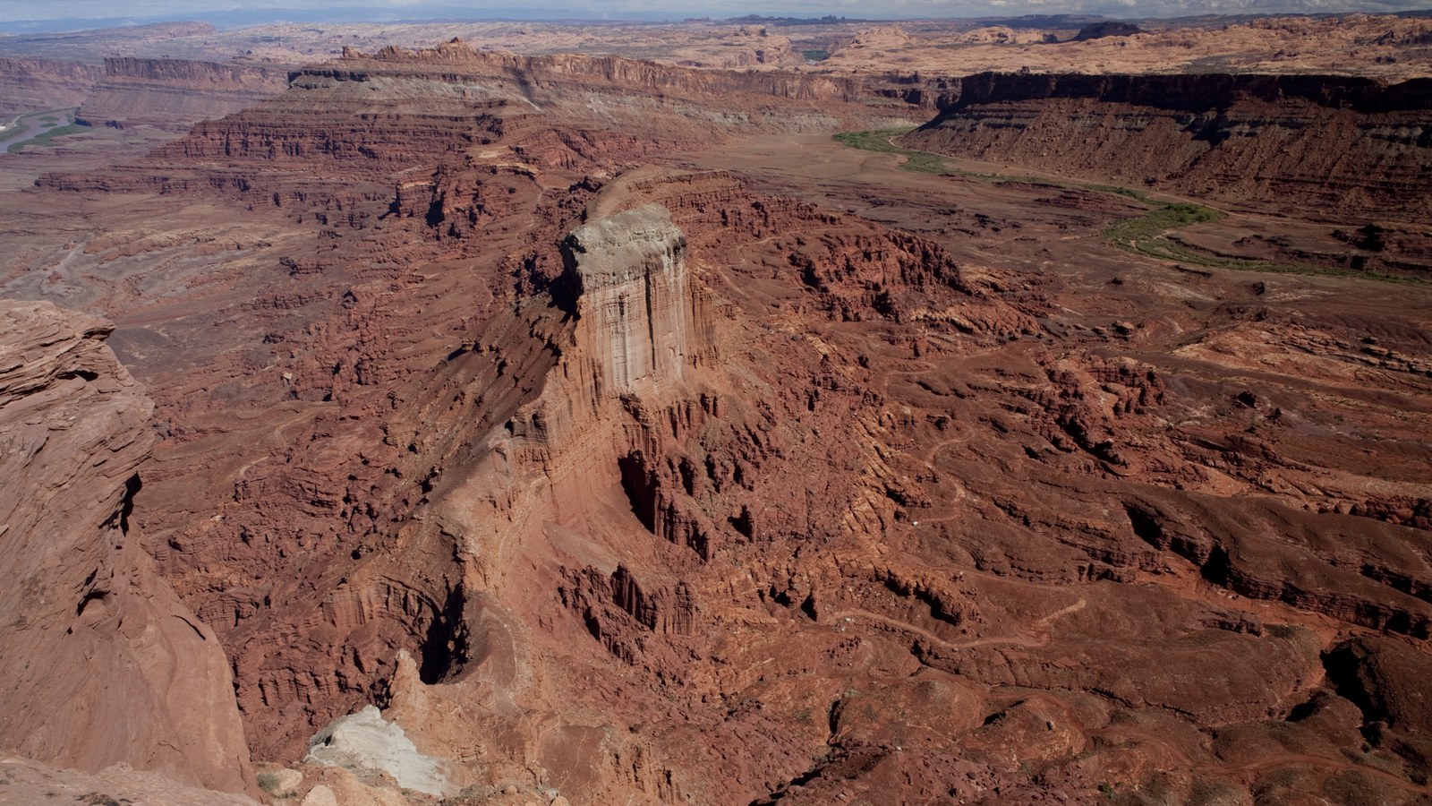 A sweeping overlook of the red rock canyon country around Moab, with a winding 4x4 track visible far below