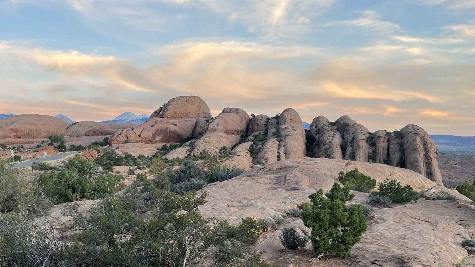 Rolling petrified sandstone domes of the Moab slickrock country with the snowcapped La Sal Mountains glowing at sunset