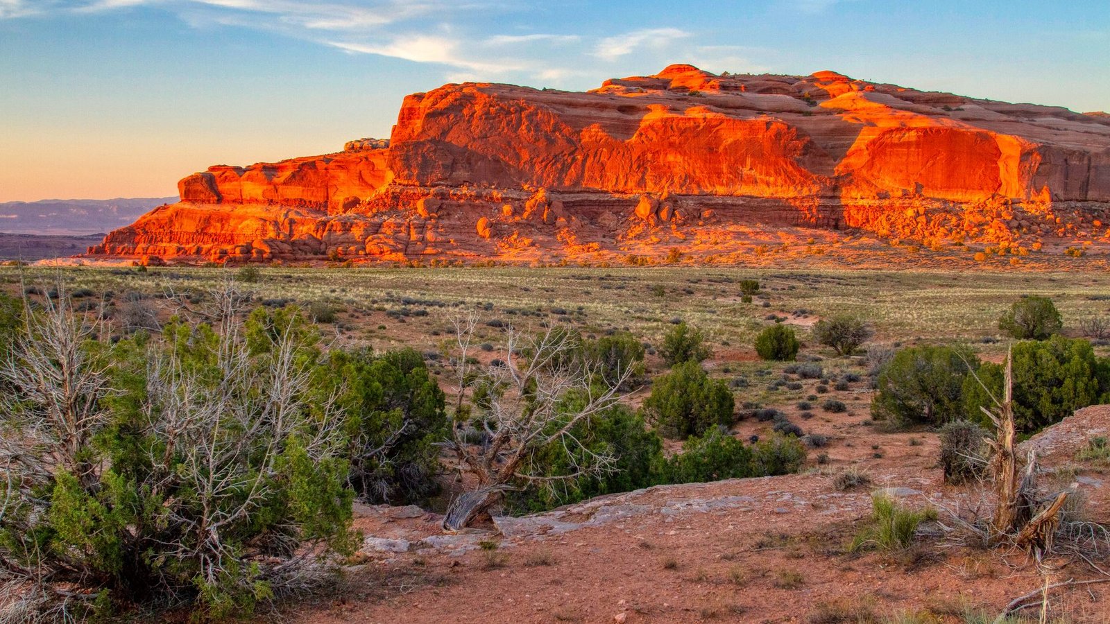 Golden hour light glowing on a red sandstone mesa in the Moab high desert, the kind of country a Poison Spider rig is built to explore