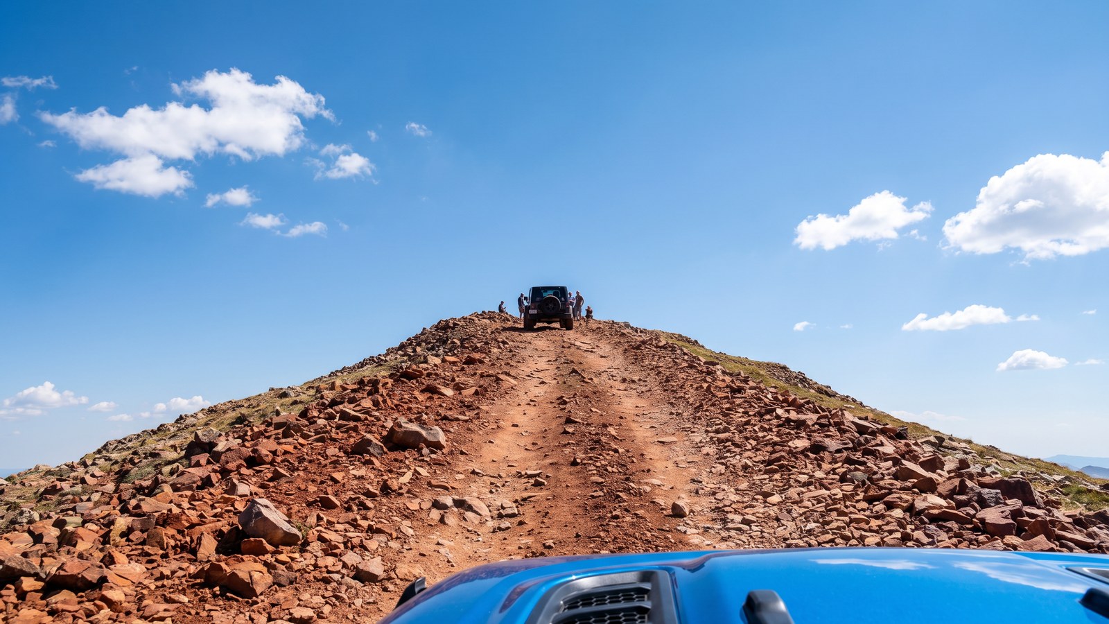 Driver's-eye POV looking up the rocky reddish alpine climb of Red Cone toward the summit, another rig on the trail ahead