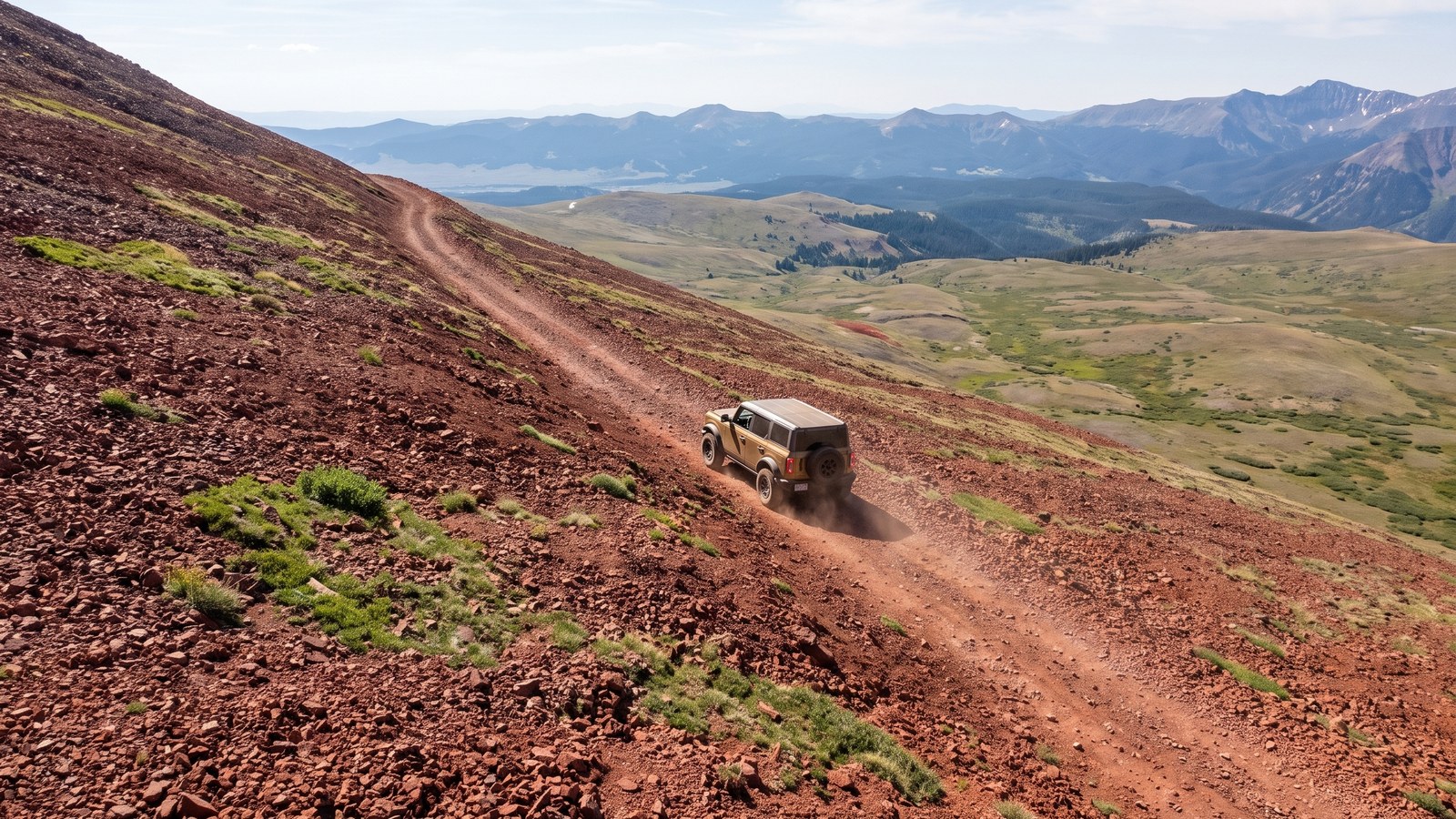 Aerial view of a rig descending the steep reddish cinder slope off the summit of Red Cone toward Webster Pass