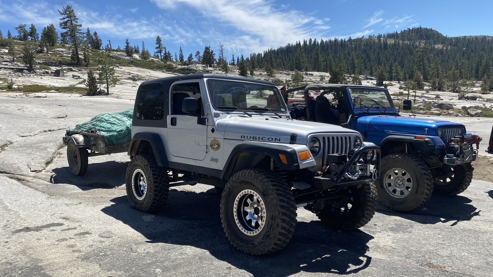 A modified Jeep with rock sliders and large tires crawling Sierra Nevada granite