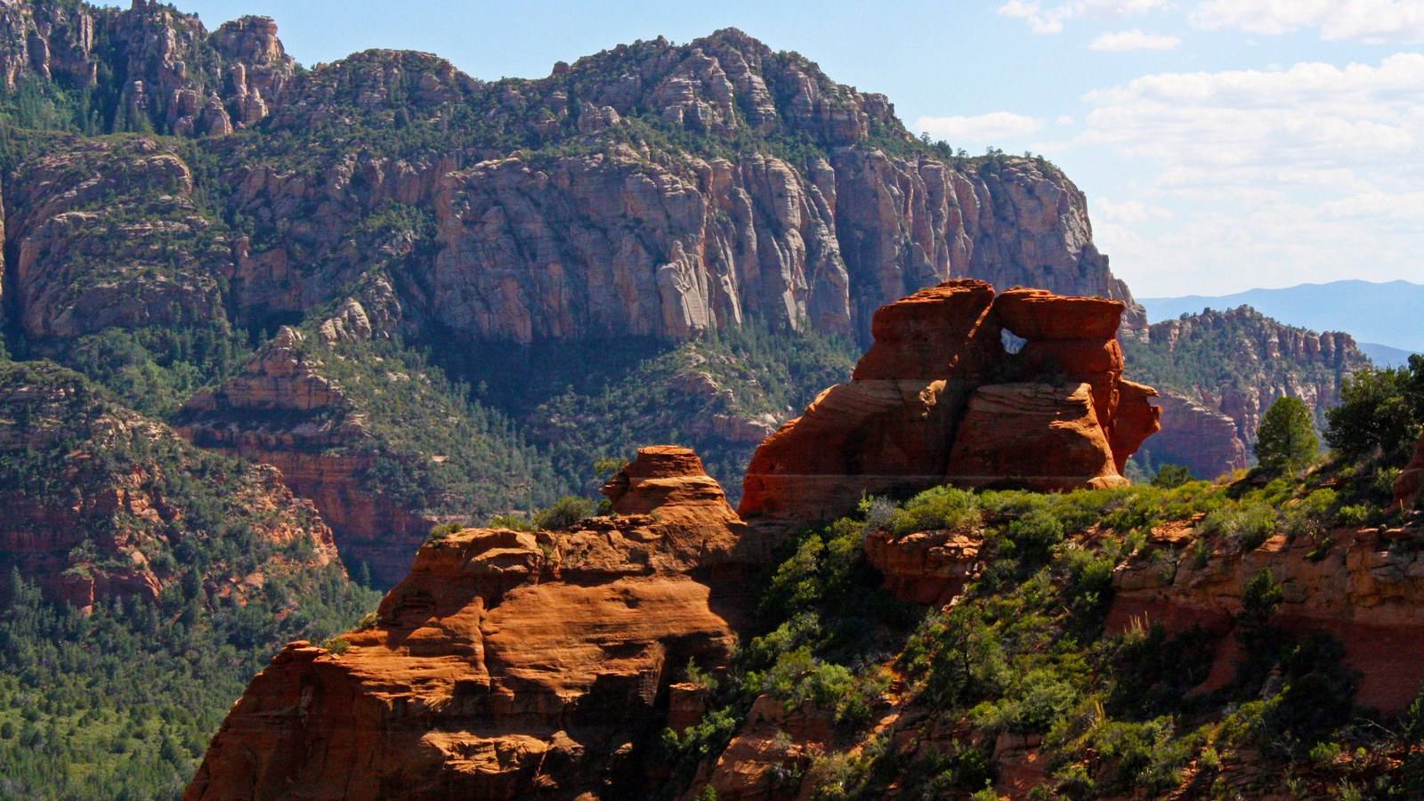 A dramatic red rock spire glowing in golden light along the Schnebly Hill corridor above Sedona, Arizona