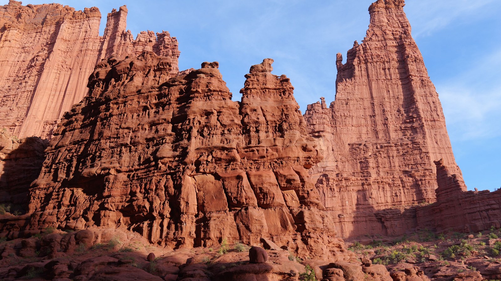 The red sandstone spires of Fisher Towers glowing in warm light near Moab, visible in the distance from the Top of the World rim