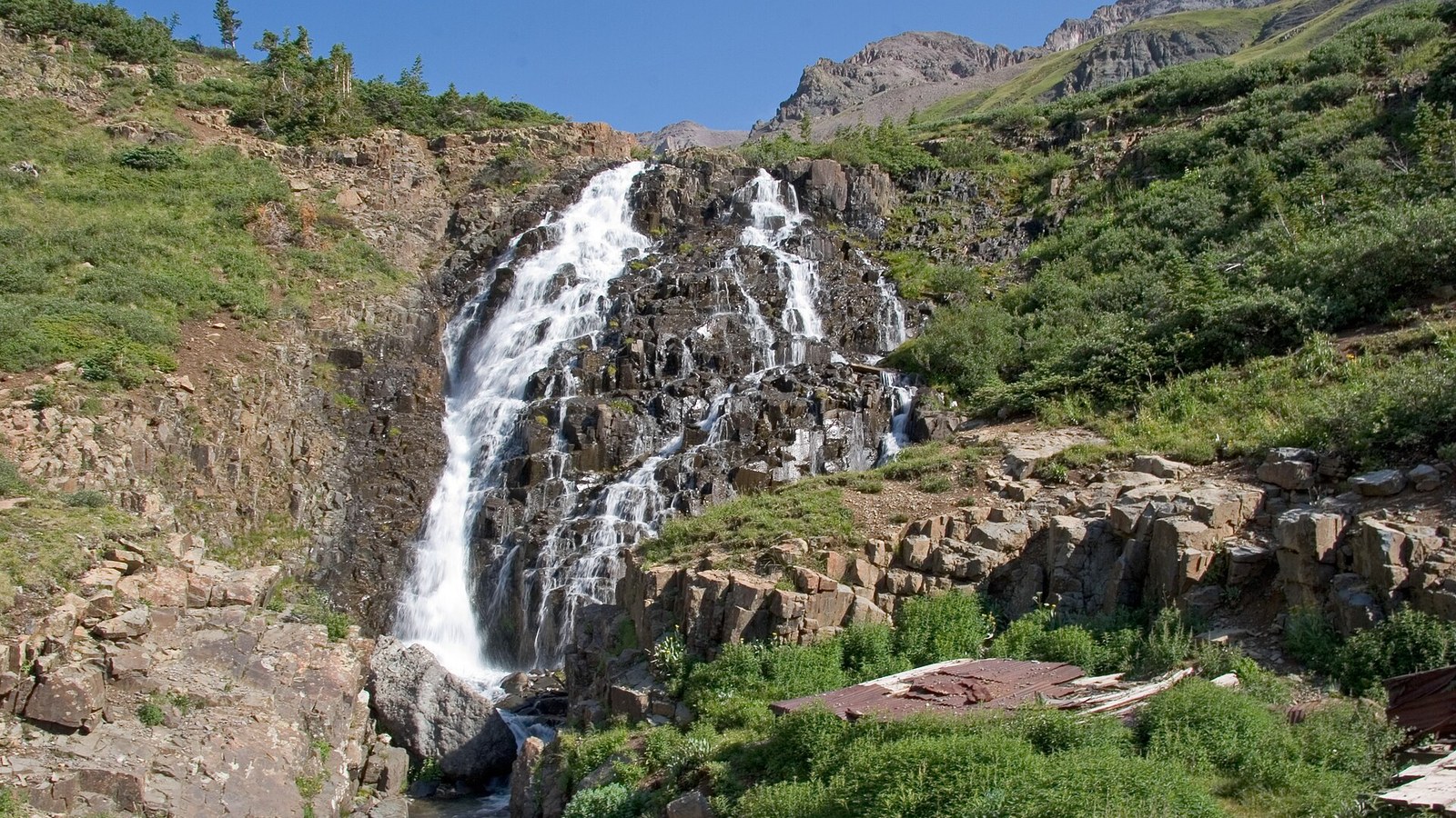 Twin Falls cascading off the tundra shelf in Yankee Boy Basin, with old mining relics at the base